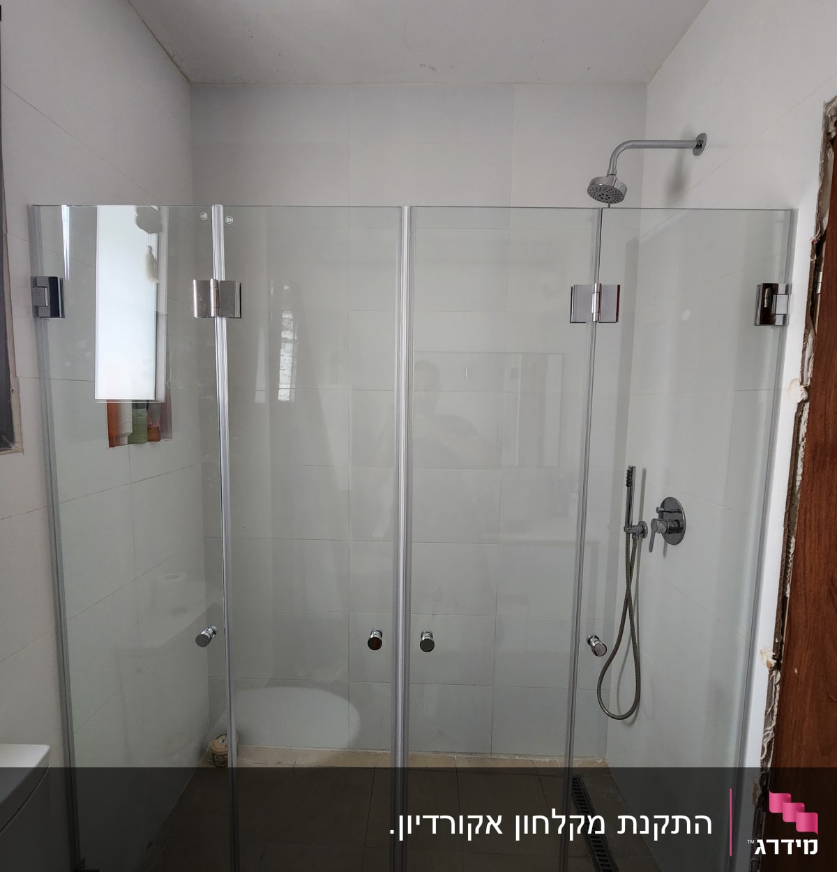 מקלחון זכוכית עם ראש מקלחת וקיר אריחים לבן